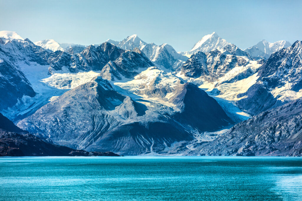 glacier bay alaska in glacier bay national park as seen from the water, bright blue water in foreground and snow capped mountains in background