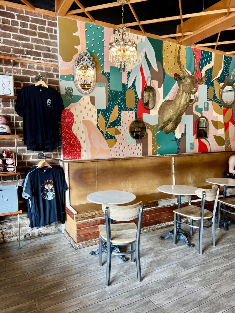 interior of the coffee fox cafes in savannah ga with small tables and bold decor including a gold deer bust