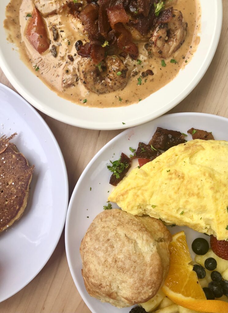 flat lay of breakfast at sunny point cafe restaurant asheville north carolina, shrimp and grits at top and omelet with biscuit on the bottom