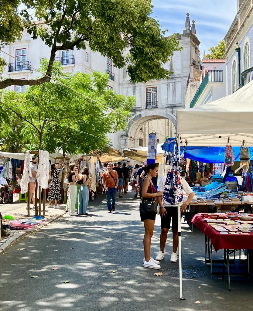 travelers browsing at feira da ladra market in lisbon portugal on a sunny day