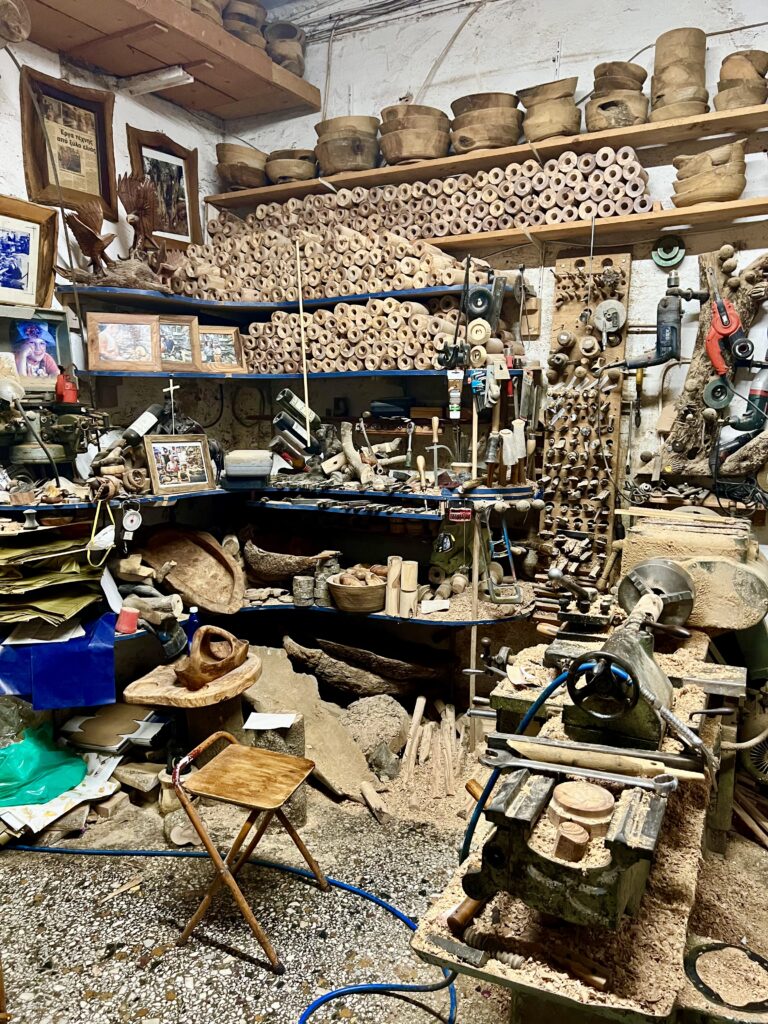 olive oil workshop in corfu greece with lots of wood piled to ceiling and a stool in the foreground
