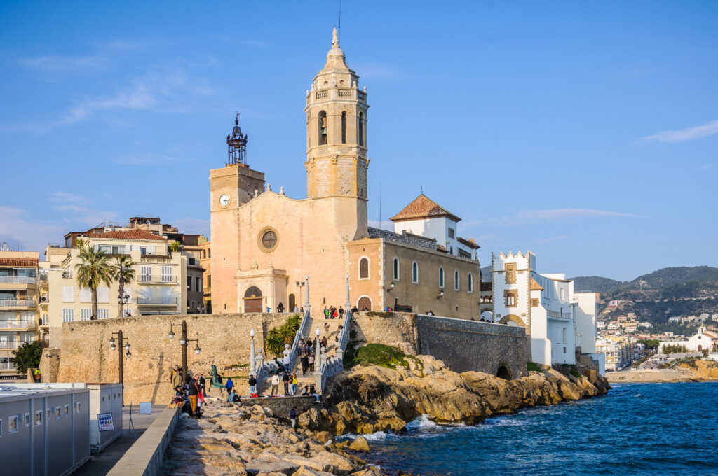 sandstone church built right against the ocean in sitges spain, one of the best towns near barcelona to visit on a day trip