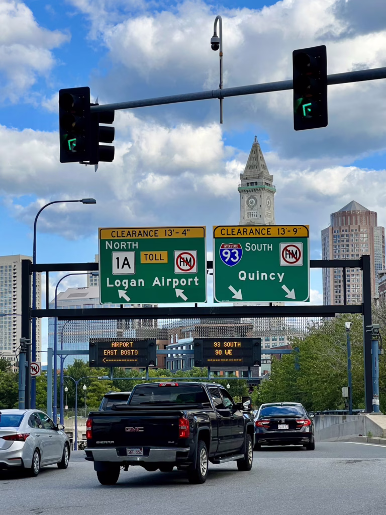view from the road in boston massachusetts showing traffic in the city and a sign for logan airport