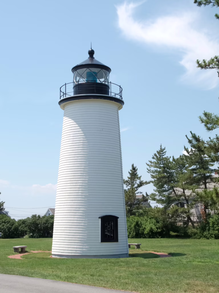 white plum island lighthouse on a grassy lawn on plum island newburport, one of the memorable day trips near boston massachusetts