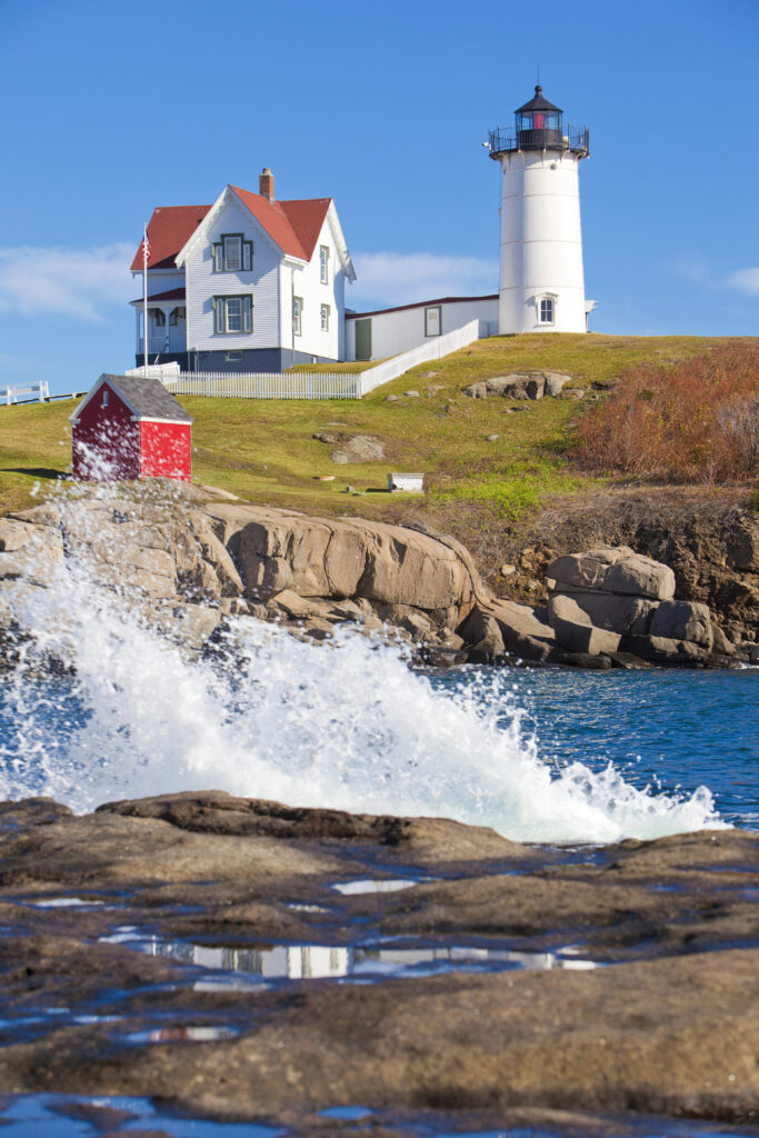 nubble lighthouse in york maine as seen from across the water on a sunny day