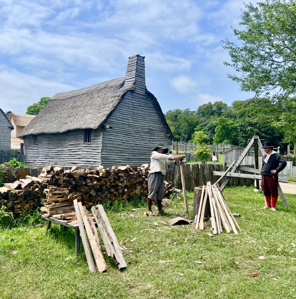 interpreters playing pilgrims chopping firewood at plimoth patuxet museums on a sunny summer day