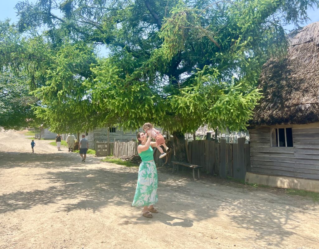 kate storm swinging her young child around in a circle in a dirt road at plimoth patuxet museums, a must-see during a one day in plymouth itinerary