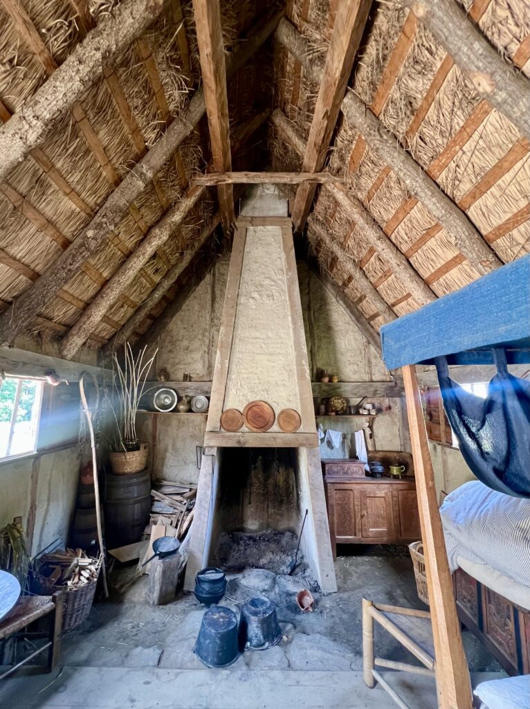 interior of a home in the 17th century english village at plimoth patuxet with fireplace in the center and thatched roof