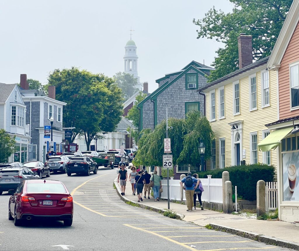 downtown rockport massachusetts showing cars driving down a curving road lined with historic buildings