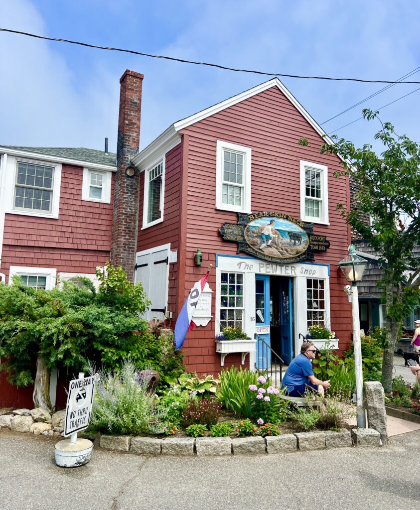 red building in bear skin neck portion of rockport ma with a sign reading "pewter shop"