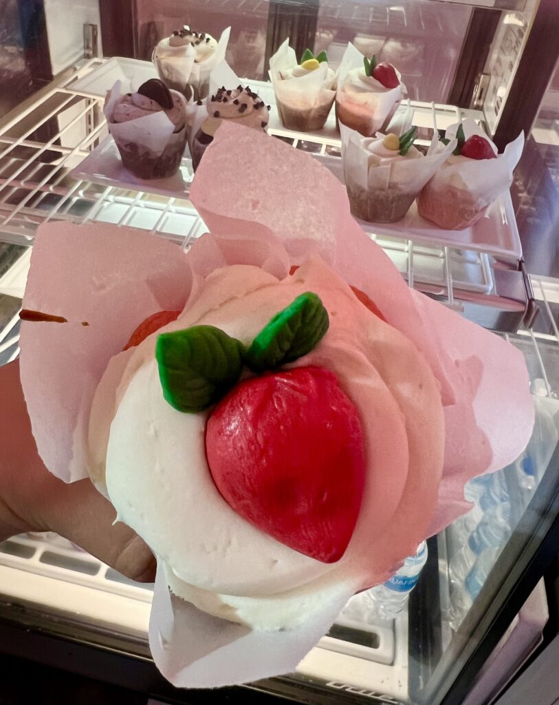 strawberry cupcake from colossal cupcakes restaurant eureka springs being held up in front of case