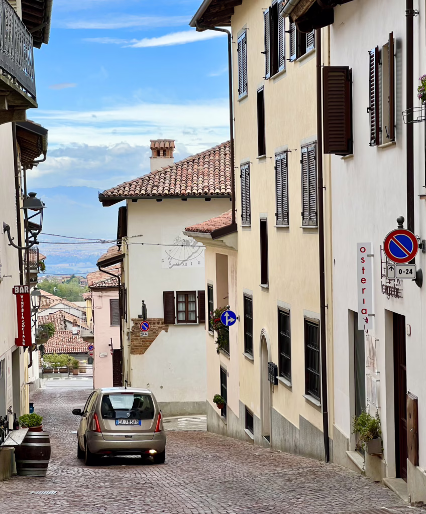 small street in la morra italy with a single small car driving down it