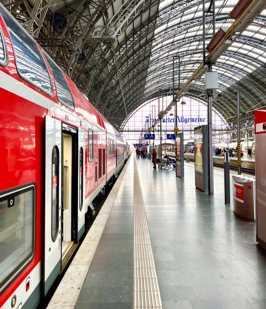 train parked at frankfurt train station with doors open waiting for people to board who are traveling europe by train