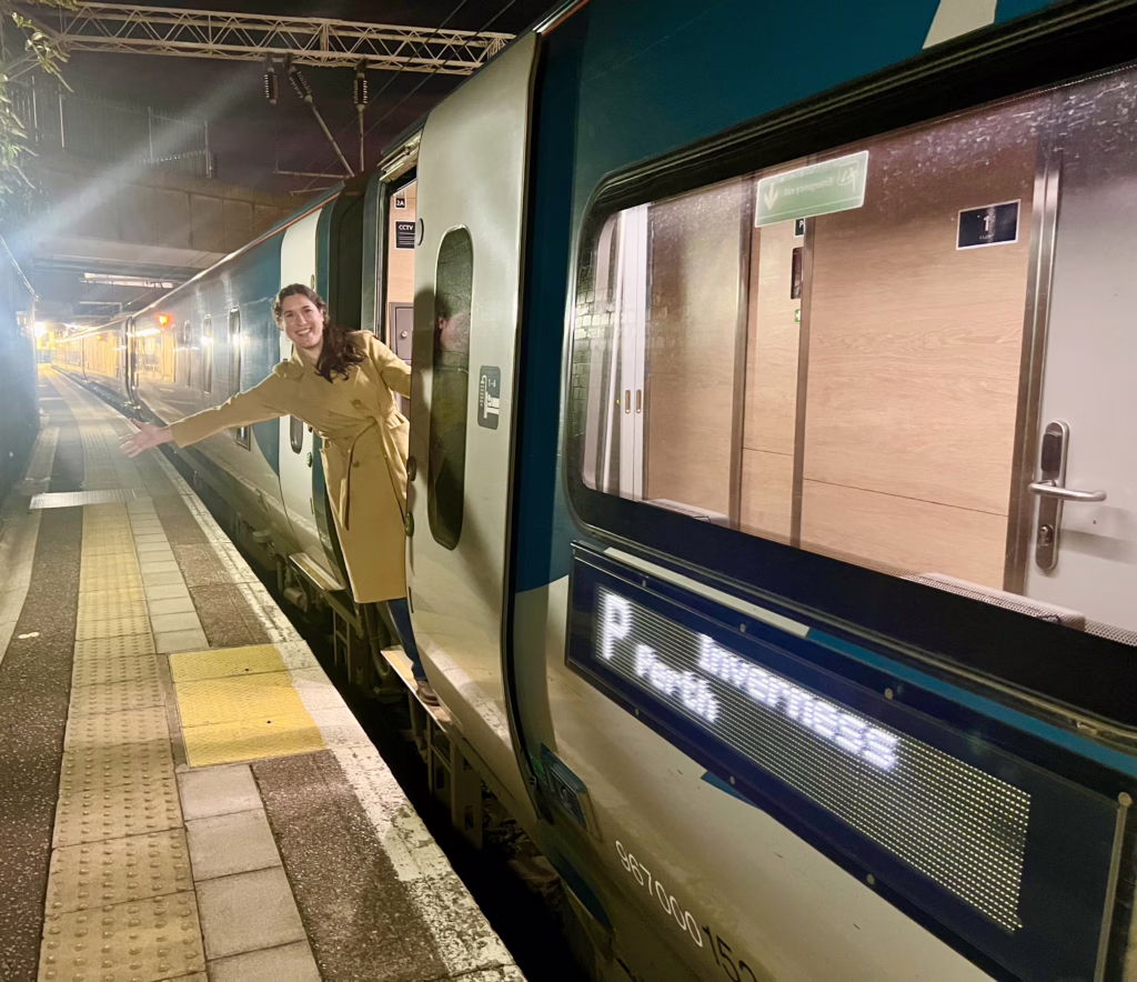 kate storm boarding the caledonian sleeper train from london to scotland and standing in doorway to train car