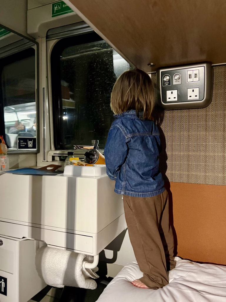 young toddler looking out the window of the caledonian sleeper train, our caledonian sleeper review with a toddler