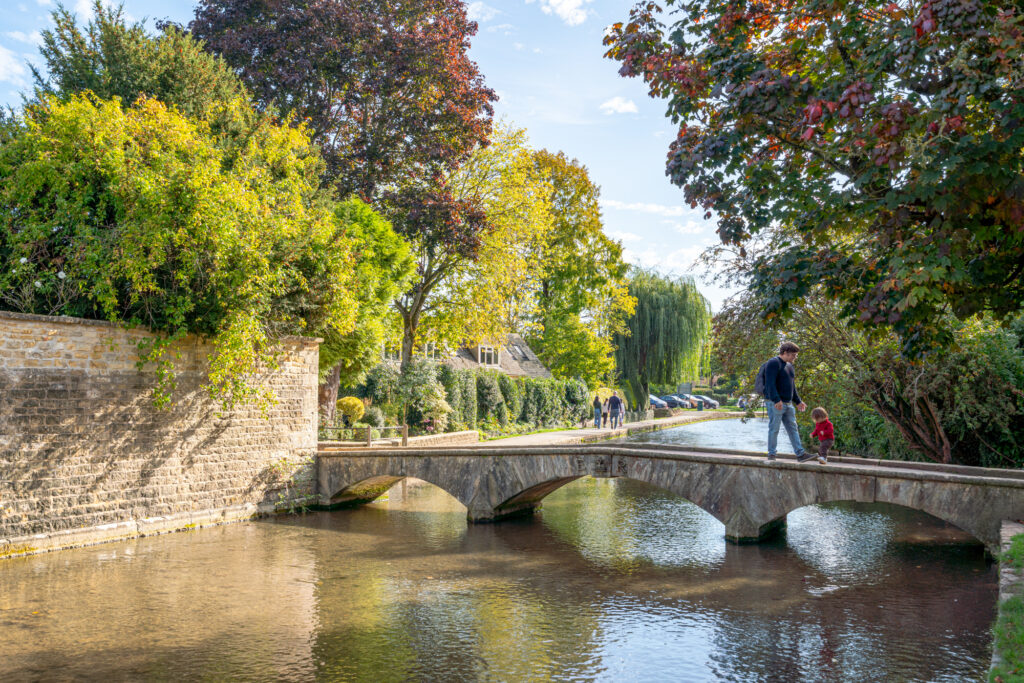 jeremy storm and his son crossing the river windrush via a stone bridge when visiting bourton on the water england