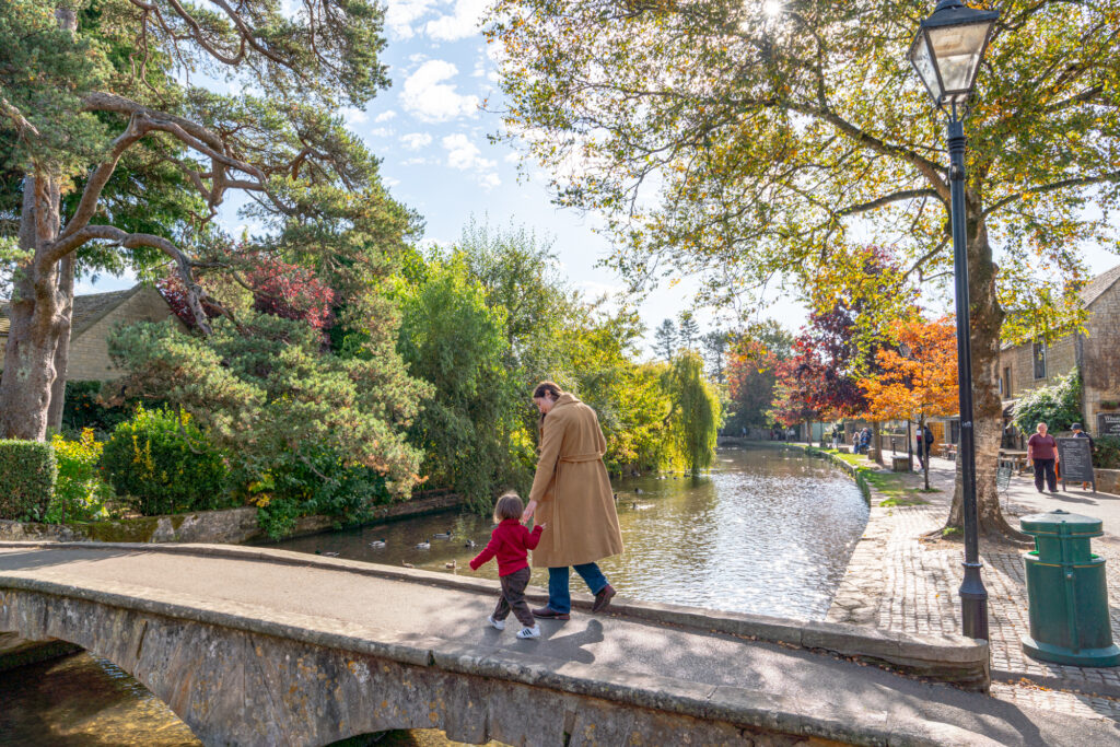 kate storm and her young son walking across a low lying stone bridge, one of the best things to do in bourton on the water cotswolds england
