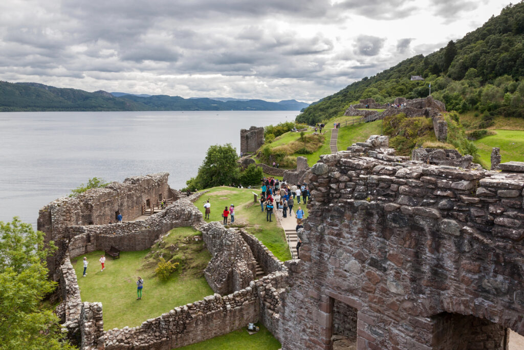 view of urquhart castle ruins from above with loch ness visible in the distance