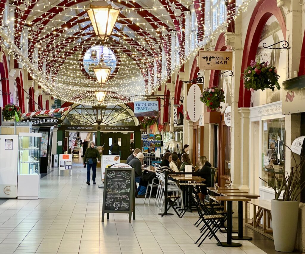 interior of the victorian market in inverness scotland with fairy lights hanging from the ceiling and a coffee shop visible ahead