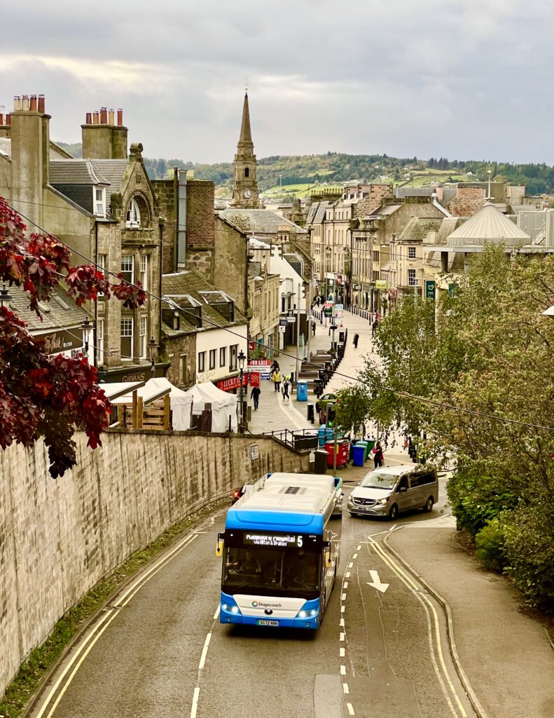 view of inverness scotland skyline from above with a bus driving down the road in the center of the photo, many of the best things to do in inverness can be reached by bus