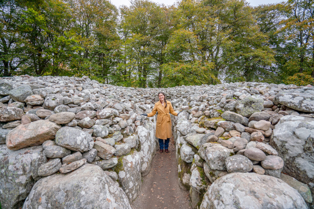 kate storm standing inside one of the large cairns at the clava cairns, one of the best things to do inverness scotland