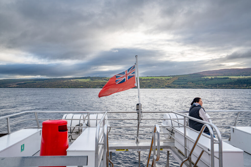 view of the back on a boat on loch ness with a flag waving in the wind in the center