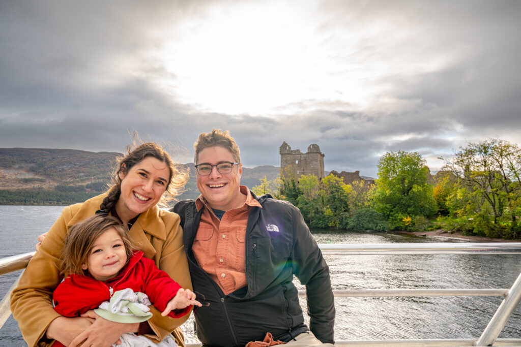 kate storm jeremy storm and their young son on a loch ness cruise in front of urquhart castle, one of the best things to do near inverness scotland