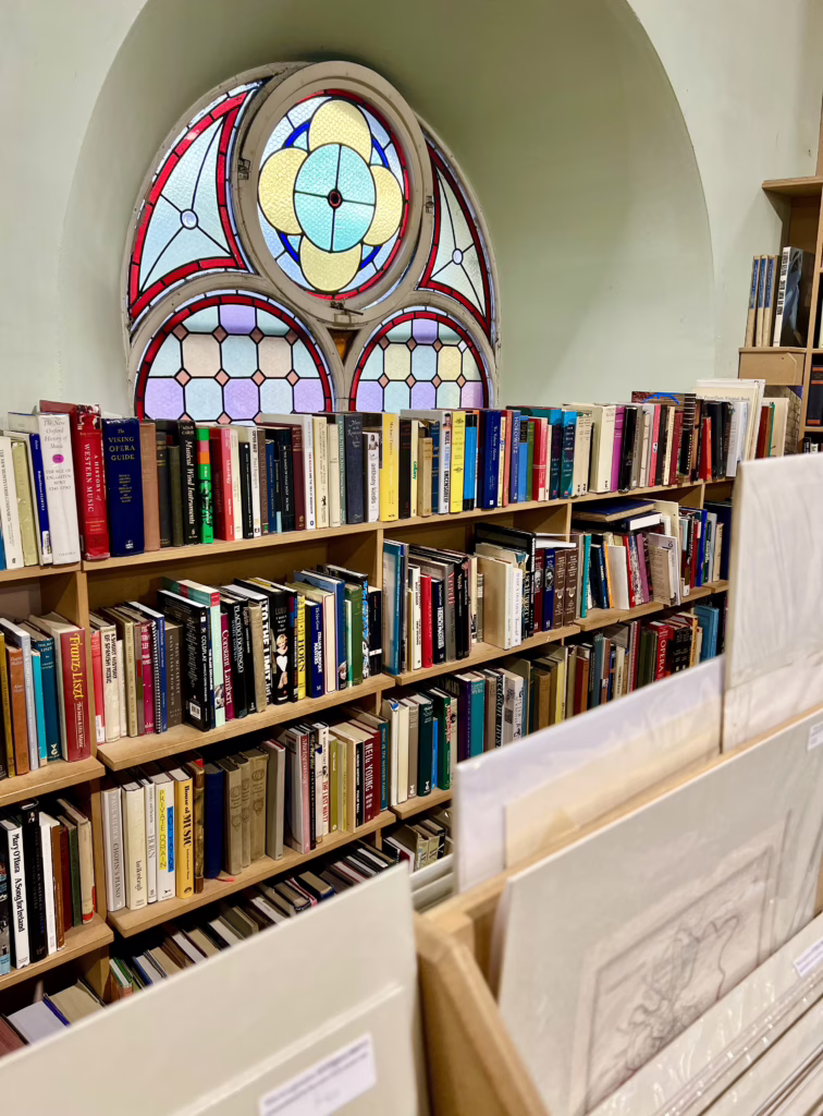 stained glass window in leakeys bookshop scotland with bookshelves and antique prints in the foreground