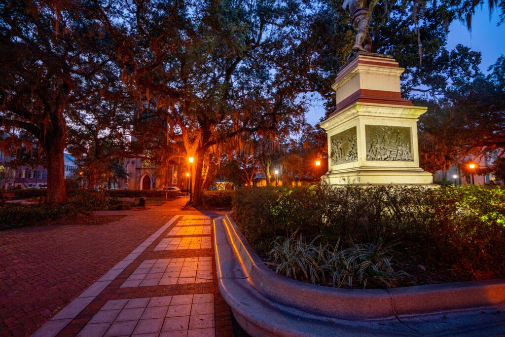 photo of a square in savannah georgia at night with lanterns lit and a statue in the foreground
