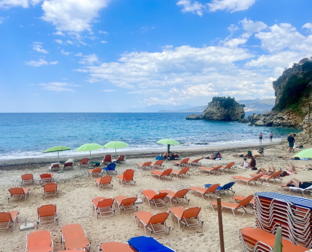 view of orange beach chairs spread across albania's mirror beach with water visible in the background
