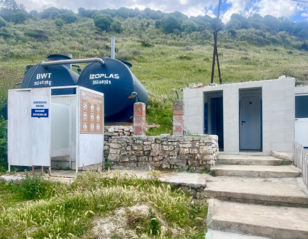 two changing stalls, showers, and toilets with a cliff behind them as seen at mirror beach