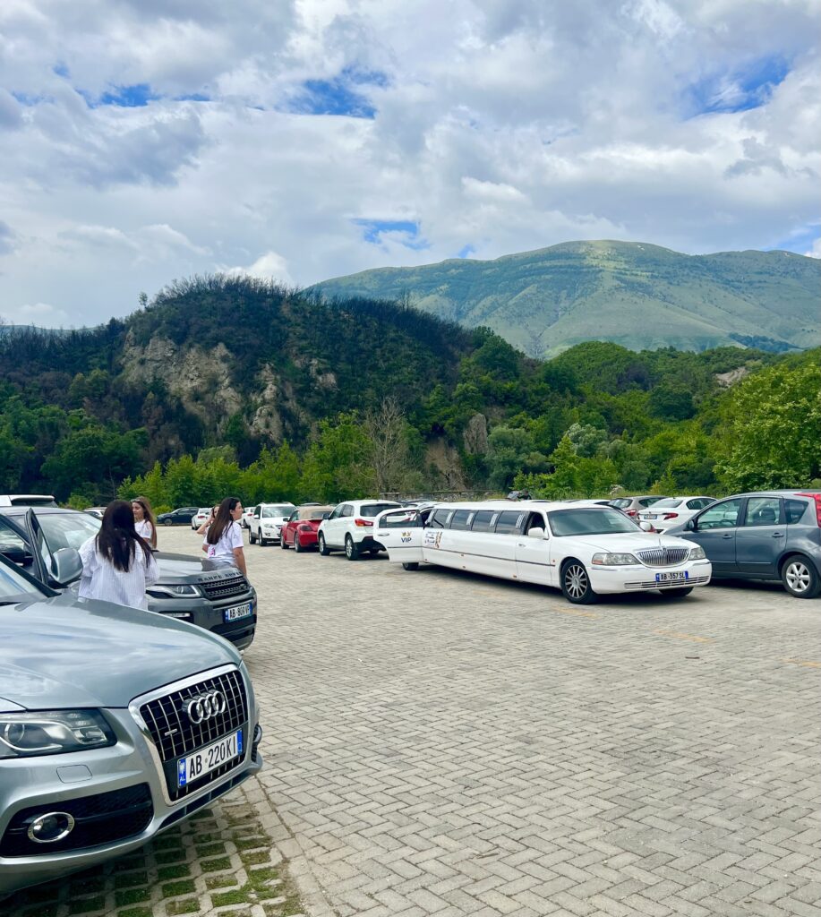 parking lot at blue eye saranda albania with a white limo in the center of the image