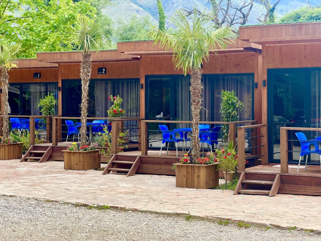 line of cabins for rent at the sarande blue eye albania, with blue patio furniture out front