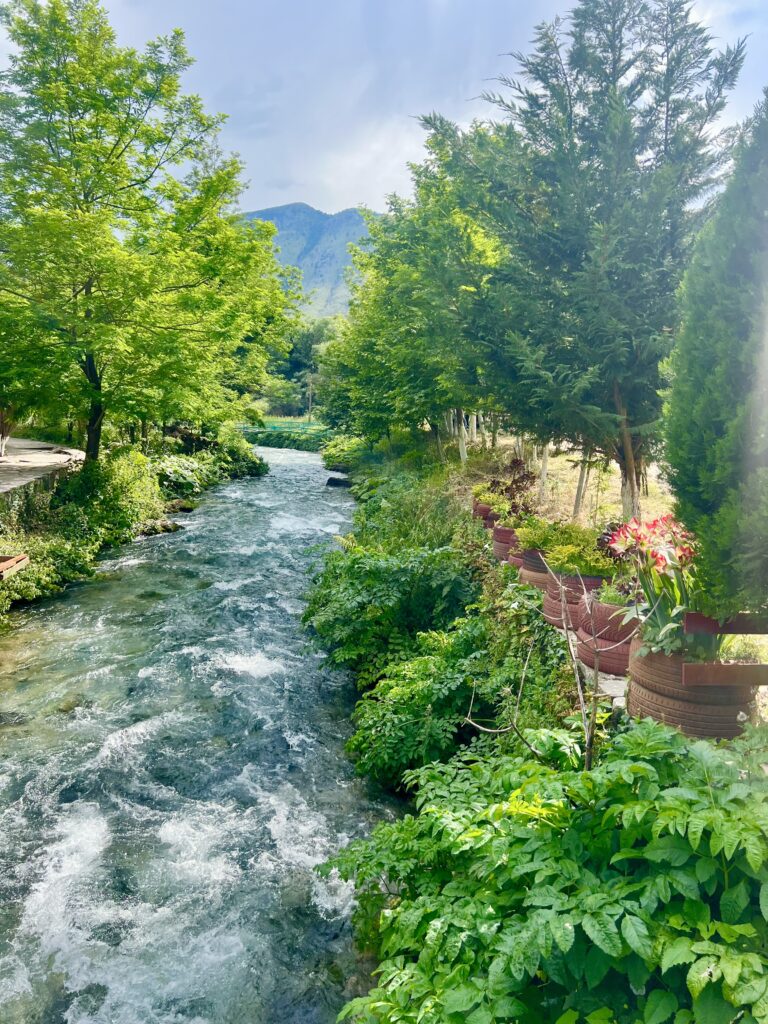 river near the sarande blue eye albania, with mountain visible in the background