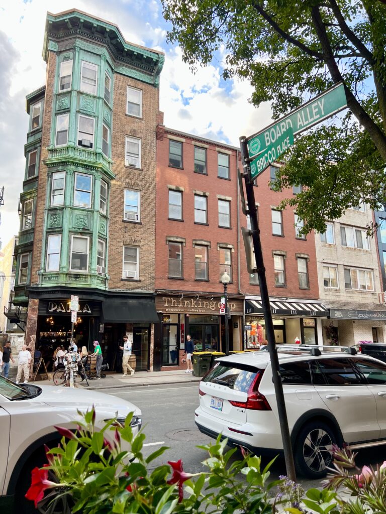 corner of board alley and bricco place in boston north end with plants and vehicles in the foreground