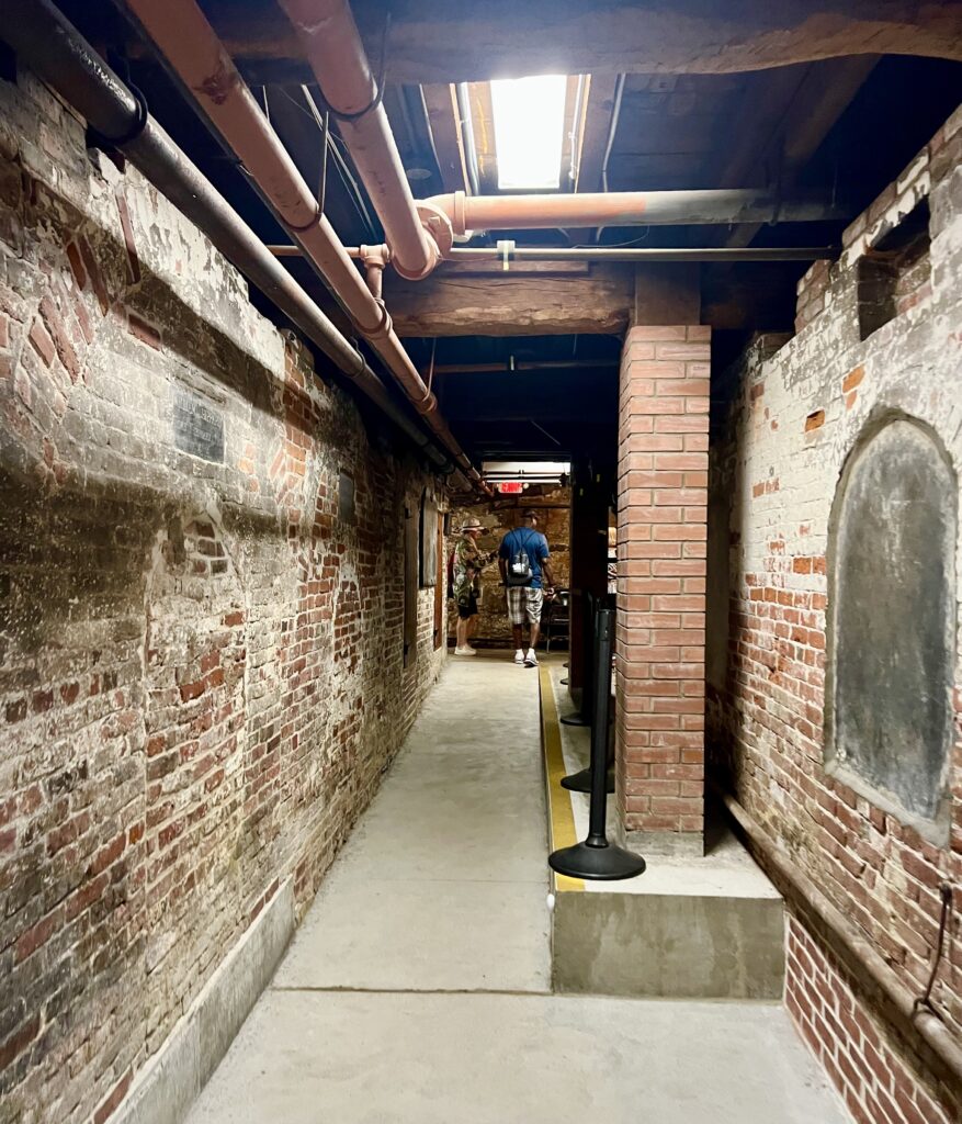 crypt of the old north church freedom trail stop in boston, with pipes running along the ceiling and brick walls to either side