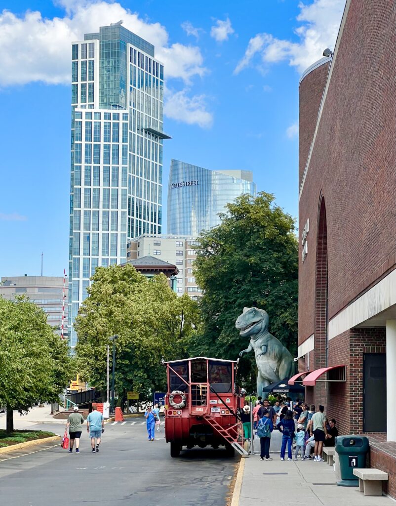 duck boat in boston ma parked at the museum of science with t rex statue and skyscraper visible in the background