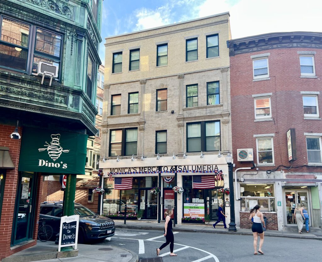 architecture of the north end boston with monica's mercato prominent and a few people crossing the street in the foreground