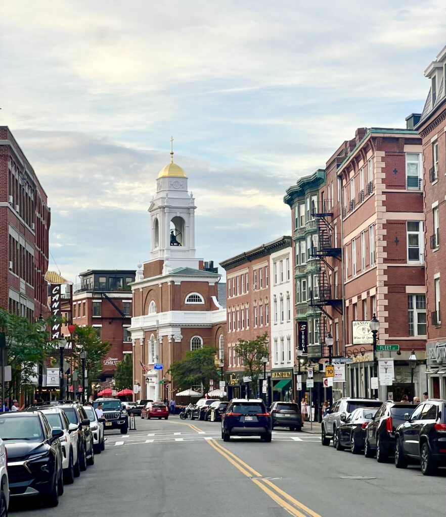 view of hanover street north end in boston massachusetts as seen from middle of the street near sunset, church prominent in the center