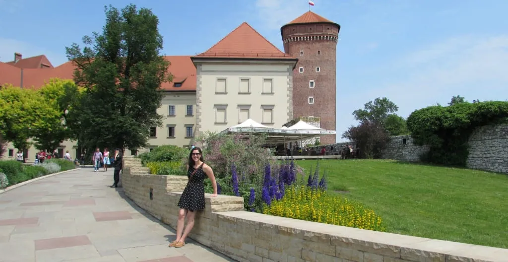 Kate Storm in a black dress standing in the courtyard of Wawel Castle--definitely stop by here during your 2 day Krakow Itinerary!