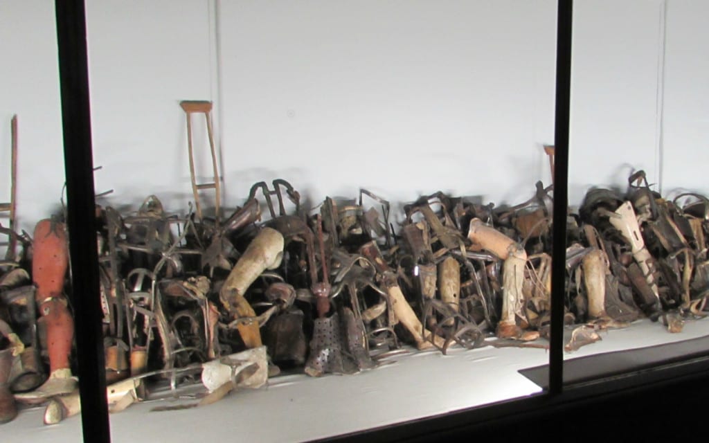 piles of canes and prosethic limbs stolen from victims of auschwitz concentration camp