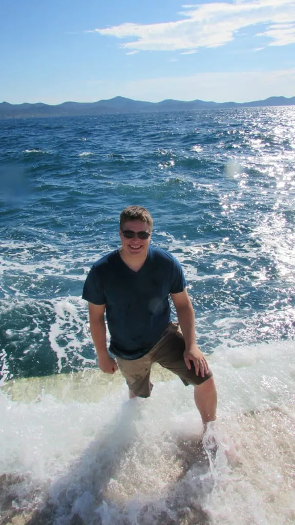 jeremy storm in a blue shirt standing on the sea organ as waves crash into him, one of the best things to do in zadar croatia