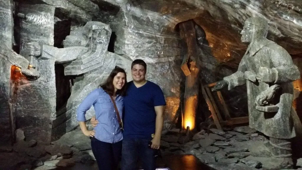 Kate Storm and Jeremy Storm posing in front of statues in Wieliczka Salt Mine, and unforgettable day trip during your 2 days in Krakow Poland