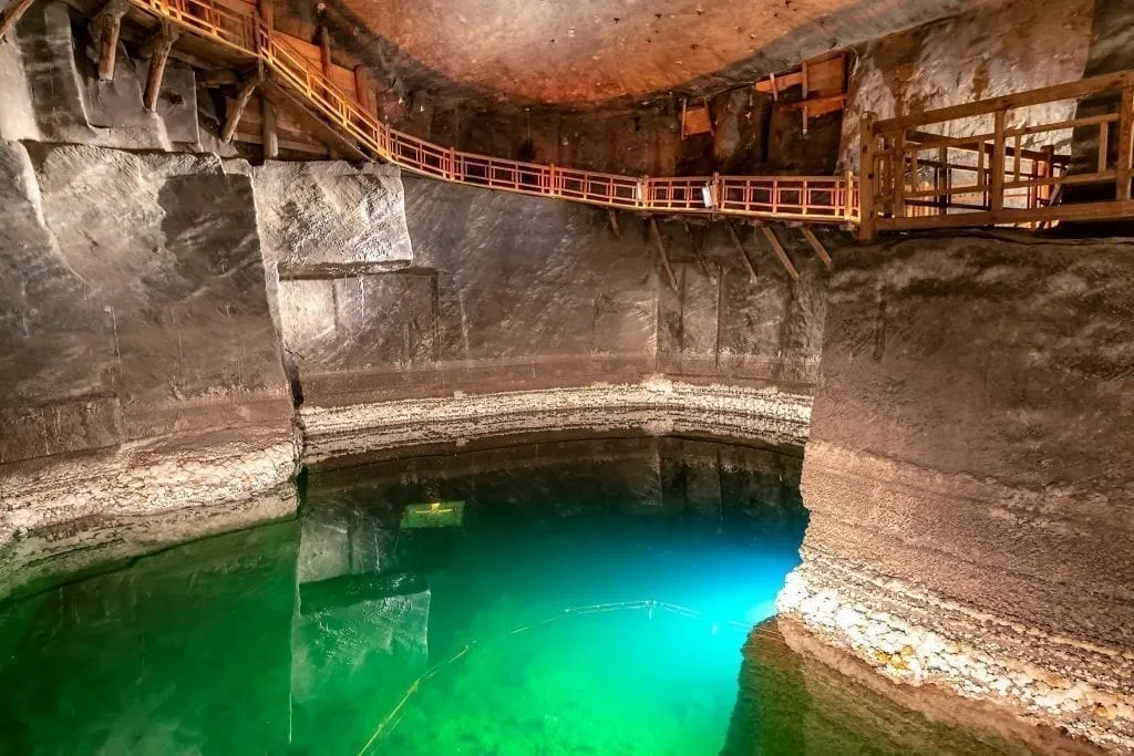 Underground lake in Wieliczka Salt Mine with wooden walking ramps around the edge. Don't miss this incredible place during your 2 day Krakow itinerary!