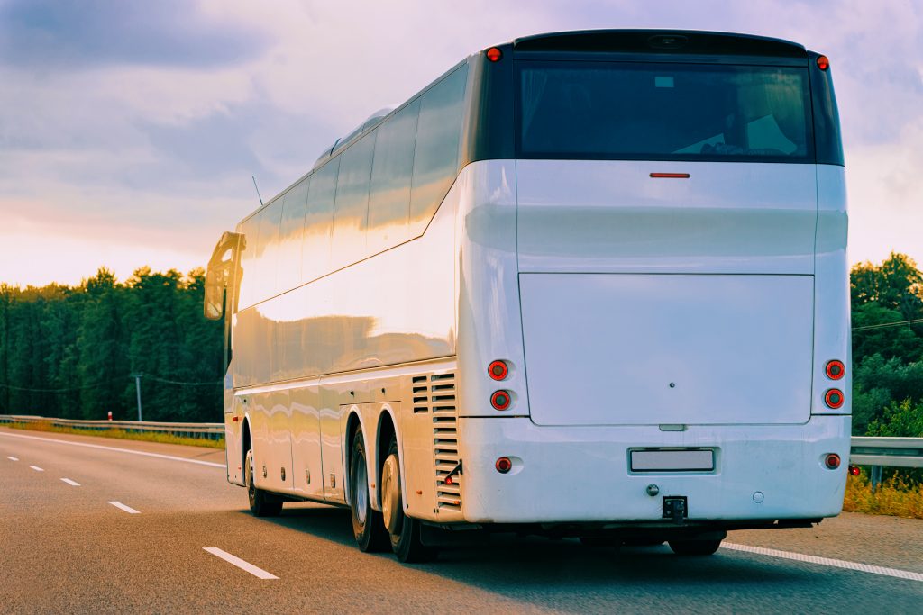 white tour bus driving down a highway in poland
