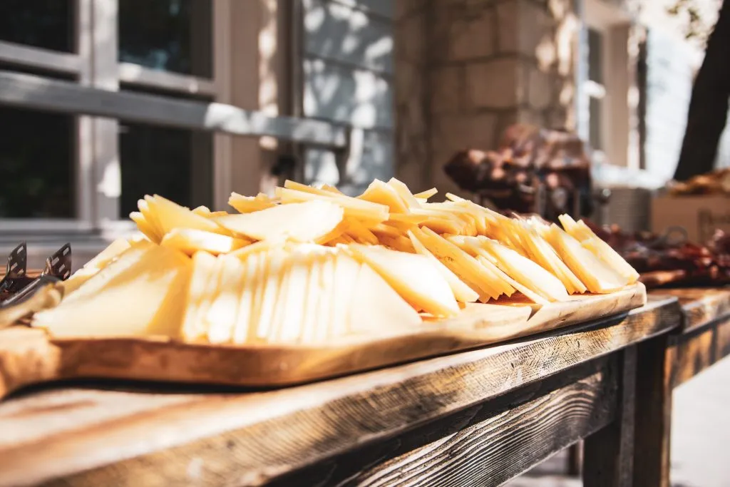 slices of pag cheese set on a platter outside on a wooden table on pag island, one of the best day trips from zadar croatia