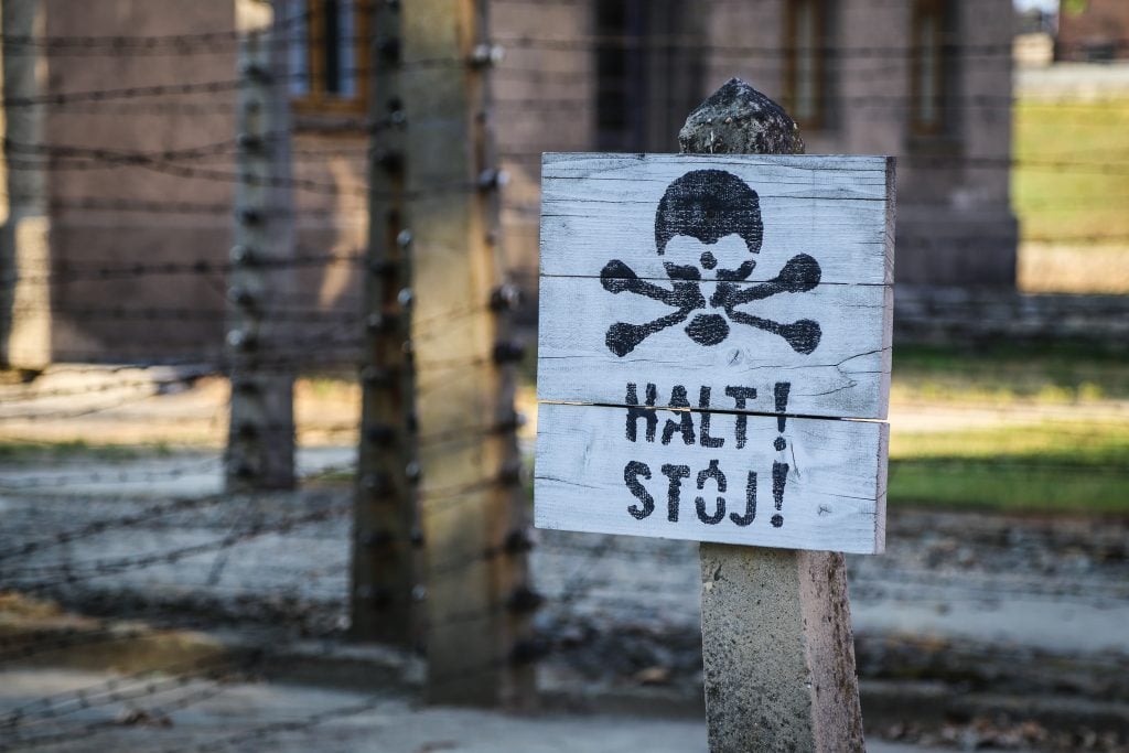 sign with skull and bones reading "halt stop" next to train tracks