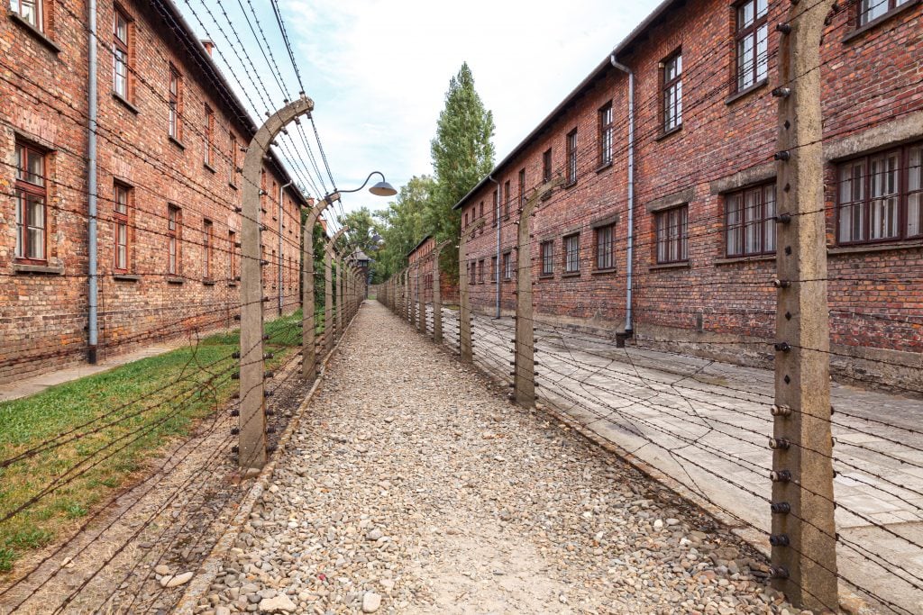 brick barracks lined with barbed wire fences in auschwitz poland