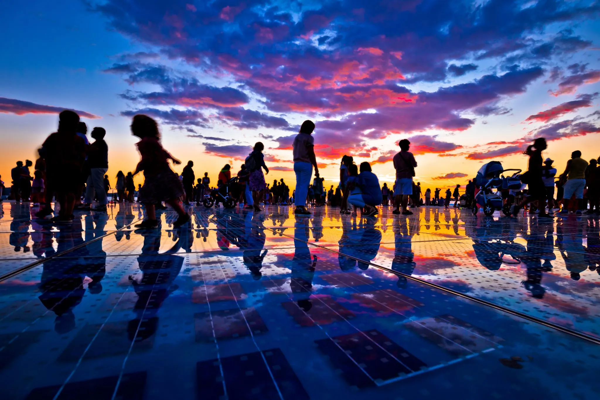 crowd of people at sunset in zadar croatia during a purple and orange sunset