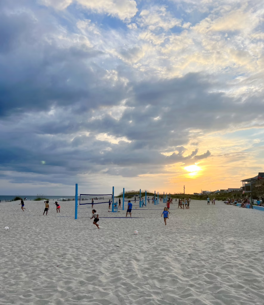 people playing on and near sand volleyball courts at the circle atlantic beach as the sunsets